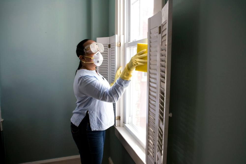 Cleaning professional in gloves wiping down a window frame